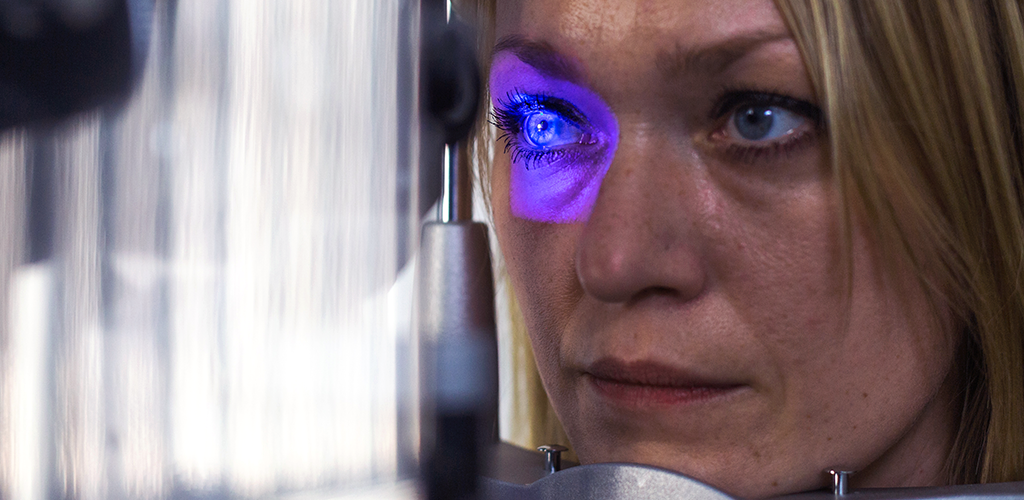 Eine Frau schaut in ein blaues Licht. Ihr Auge wird gerade in der KRH Augenklinik untersucht